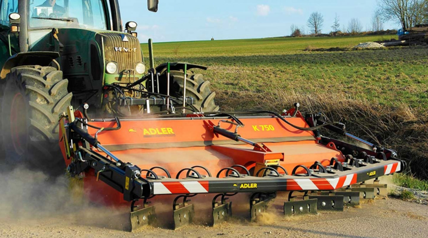 Kehrmaschine K750 von ADLER Arbeitsmaschinen im Einsatz in der Landwirtschaft mit Kratzvorrichtung im Frontanbau am Traktor.